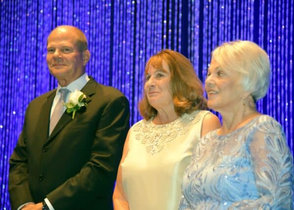 Three people standing on stage smiling at the annual gala