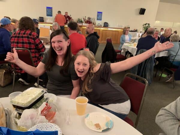 tow women at the trivia night raising their hands and colebrating