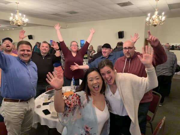 a group or participants at the trivia night raising their hands and colebrating