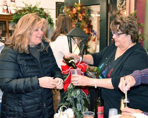 Two women smiling pouring wine at a fundraising event
