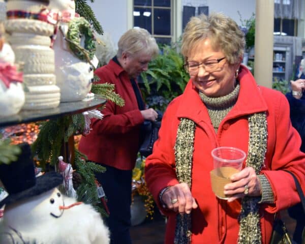 A woman smiling looking at some Christmas tree ornaments at a fundraising event
