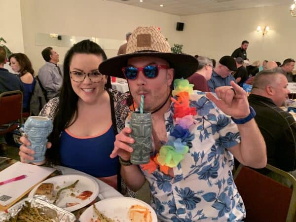 a man and women in Hawaiian shirts enjoying drinks at the trivia night