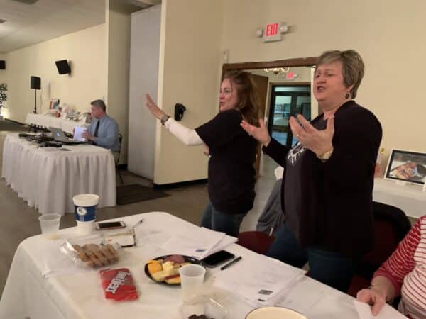 two women standing and singing at the trivia night