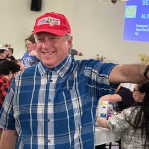 A smiling man dressed in a Forrest Gump costume participating in a Trivia Night pointing his thumb down