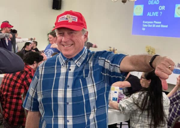 A smiling man dressed in a Forrest Gump costume participating in a Trivia Night pointing his thumb down